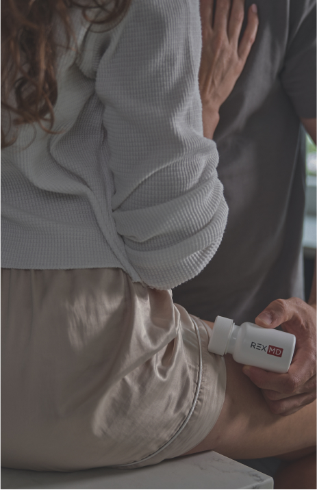 A man is holding a Rex MD pill bottle while sharing an intimate moment with his partner